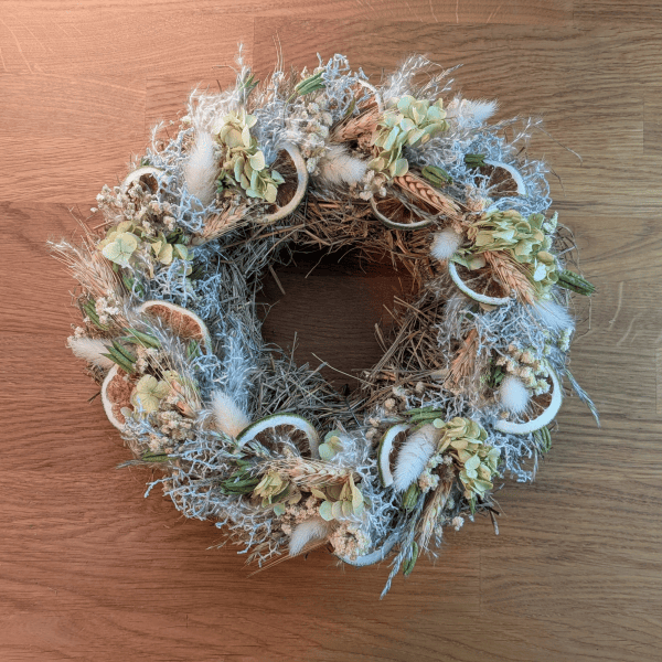 Trockenblumenkranz mit Limetten und Schleierkraut auf Strohunterlage